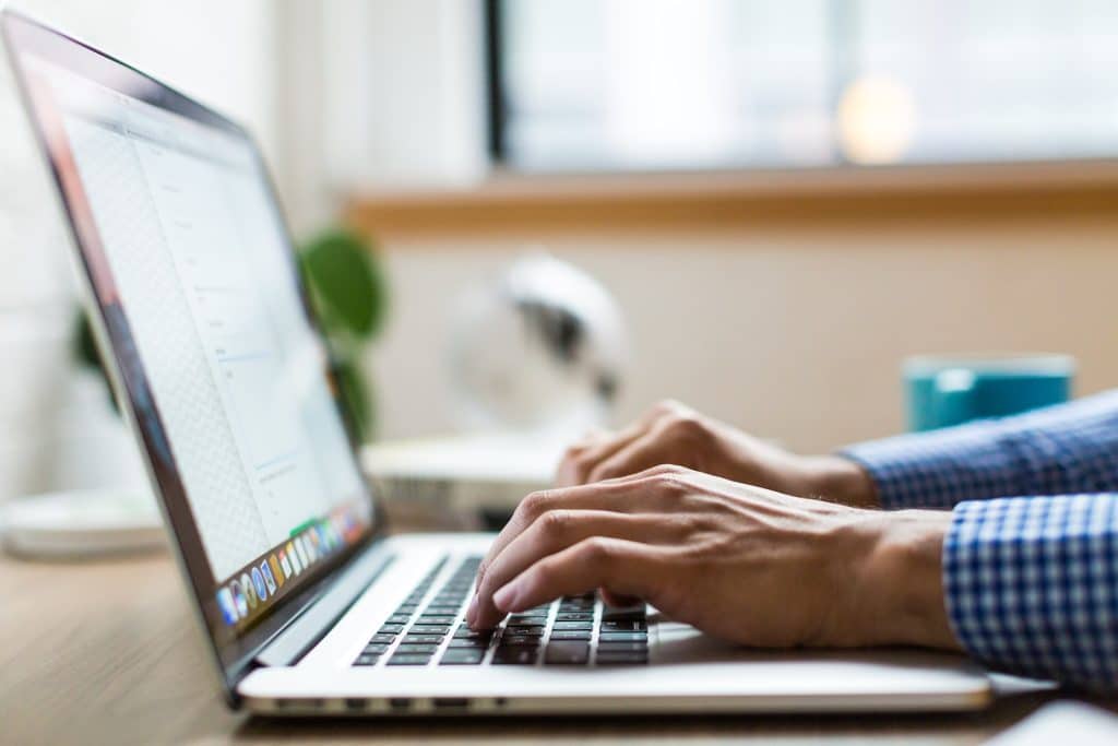 osoba koja tipka na srebrnom macbooku
